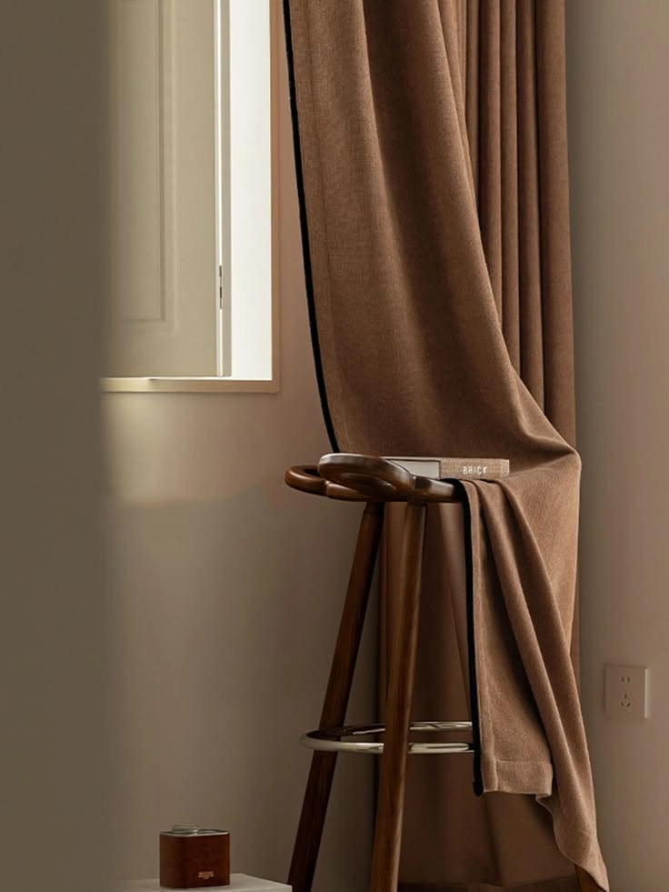 Brown curtain over a wooden stool with a book cozy style from a Malappuram furniture shop